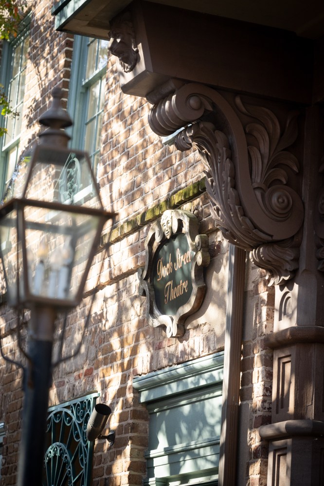 Ornate theater sign on brick building with lamp post and decorative facade.