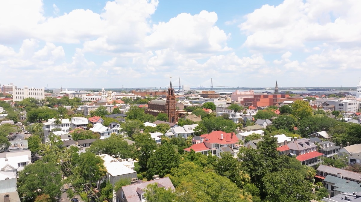 Aerial view of a cityscape with church, bridge, houses, and greenery.